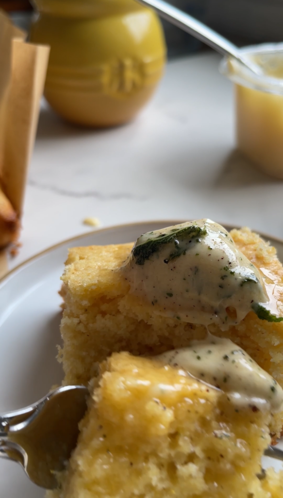 Brown butter sage compound butter with bits of sage, melting over a slice of fresh cornbread