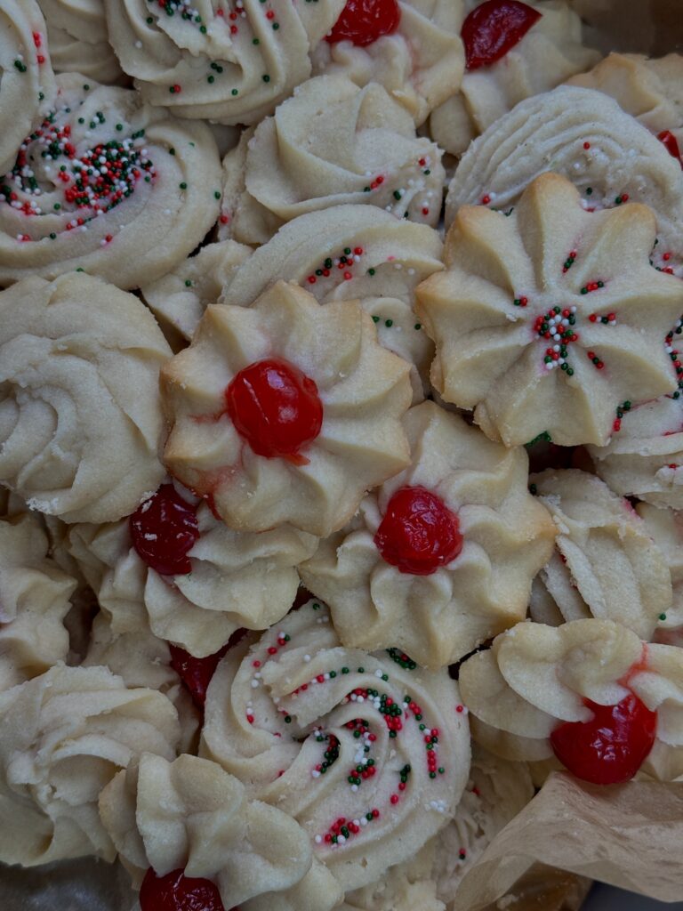 Classic Butter cookies with sprinkles and a maraschino cherry in a pile on a cookie tray