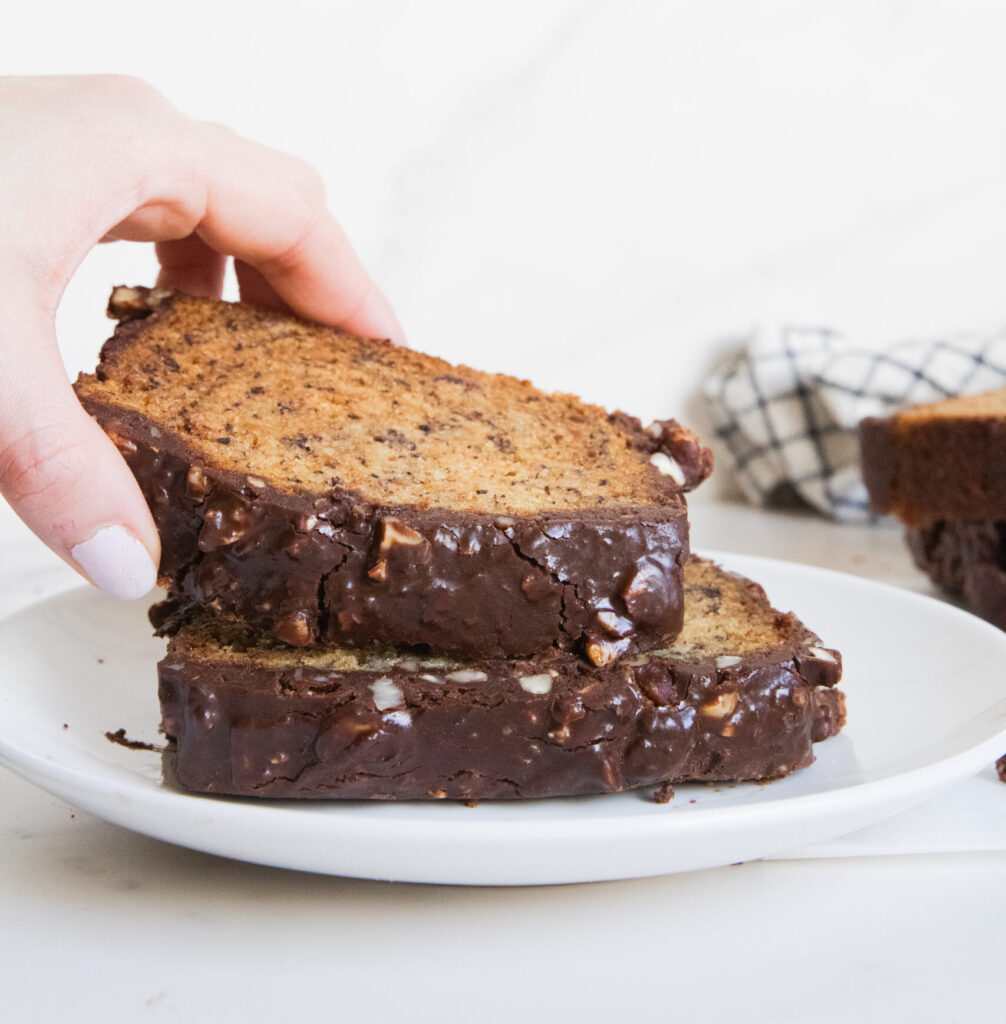 Two slices of chocolate Hazelnut Crunch Banana-Bread being lifted up by a hand