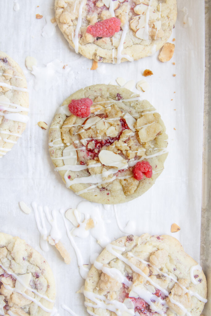 Raspberry Almond Coffee Cake Cookies on a sheet pan with drizzle of almond frosting